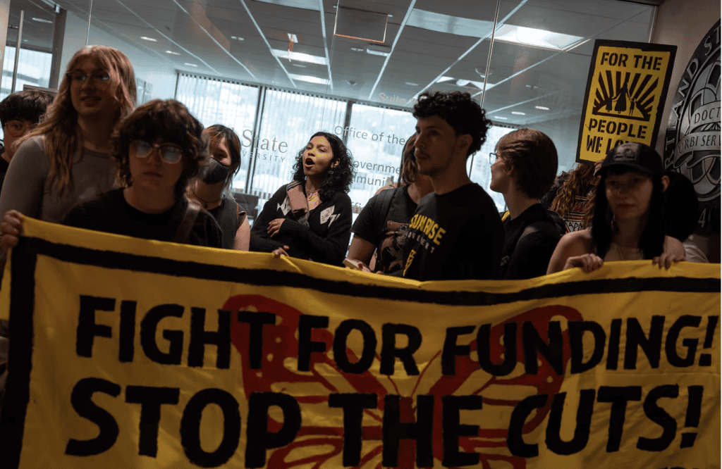 Group of students holding a banner that reads: Fight for Funding! Stop the Cuts!